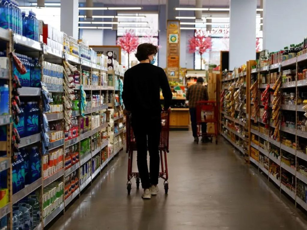 Persona caminando en el supermercado, viendo los precios afectados por la inflación en Córdoba.